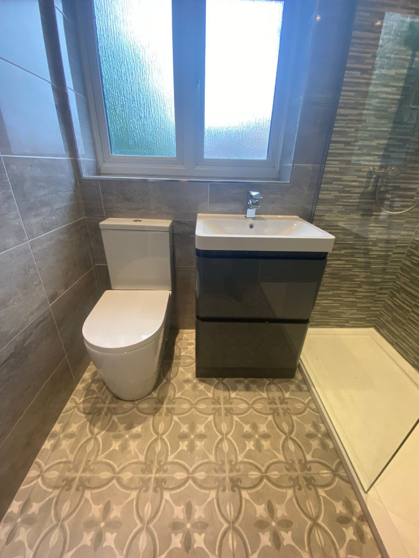 Renovated bathroom with patterned tiles, vanity unit, and shower enclosure in Manchester
